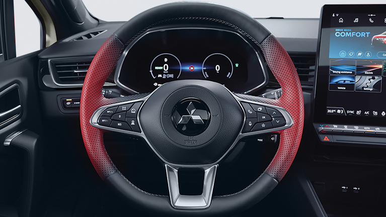 Frontale Nahaufnahme des sportlich gestalteten Multifunktionslenkrads im Mitsubishi ASX Select mit roten Griffbereichen, integrierten Bedientasten und digitalem Kombiinstrument sowie großem Touchscreen rechts im Hintergrund.