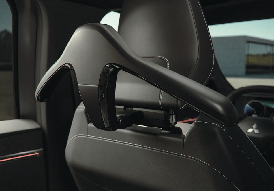 Heckansicht eines grauen Mitsubishi Eclipse Cross mit montiertem Fahrrad-Heckträger und zwei Fahrrädern, geparkt auf einer Landstraße in bergiger Landschaft.