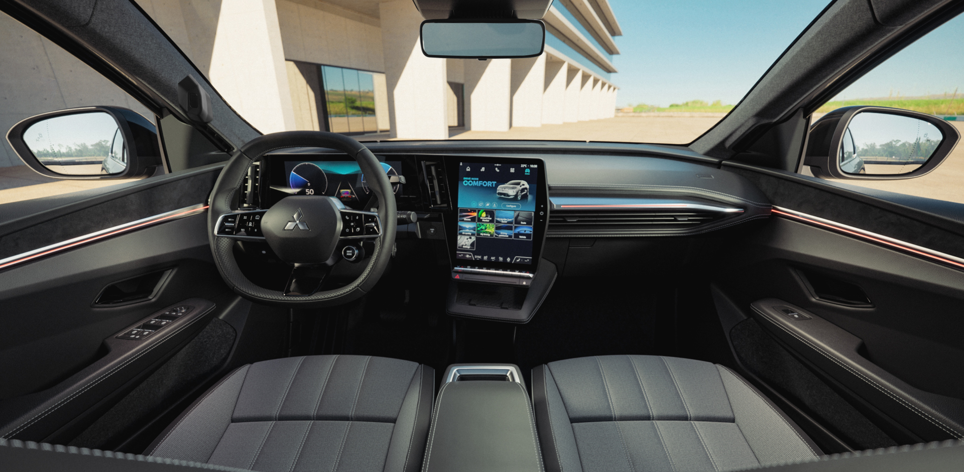 Frontale Innenansicht der Eclipse Cross Intro Edition: Blick von den Vordersitzen auf Multifunktionslenkrad, großes zentrales Touchdisplay und moderne Armaturentafel; durch die Frontscheibe sind ein modernes Gebäude und der helle Himmel zu sehen.