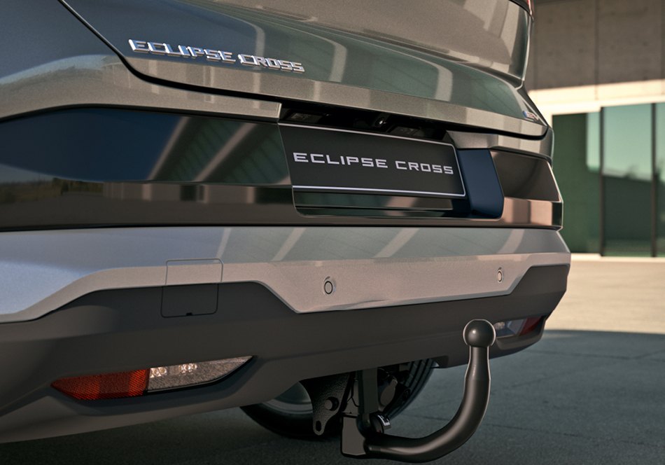 Detailaufnahme des Hecks eines Mitsubishi Eclipse Cross mit montierter Anhängerkupplung, geparkt vor einem modernen Gebäude.
