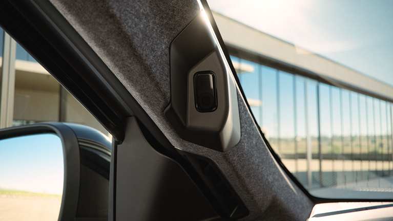 Detailaufnahme der A‑Säule im Innenraum der Eclipse Cross Intro Edition mit integrierter Front- bzw. Assistenzkamera; durch das Seitenfenster sind moderne Glasarchitektur und blauer Himmel zu sehen – verdeutlicht die fortschrittlichen Fahrerassistenzsysteme des Fahrzeugs.