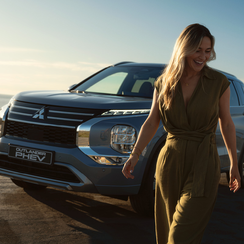 Mitsubishi Outlander mit Frontscheibe und einer Frau neben dem Fahrzeug